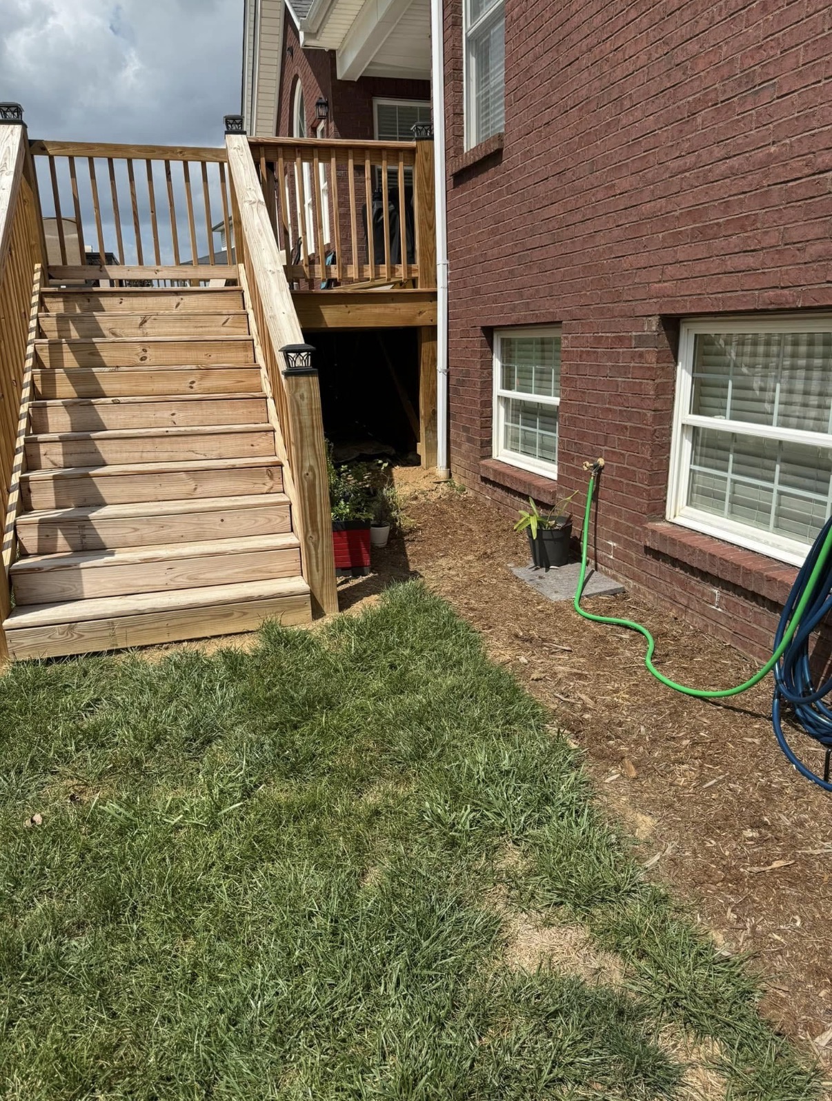 Deck stairs against brick home with fresh landscaping